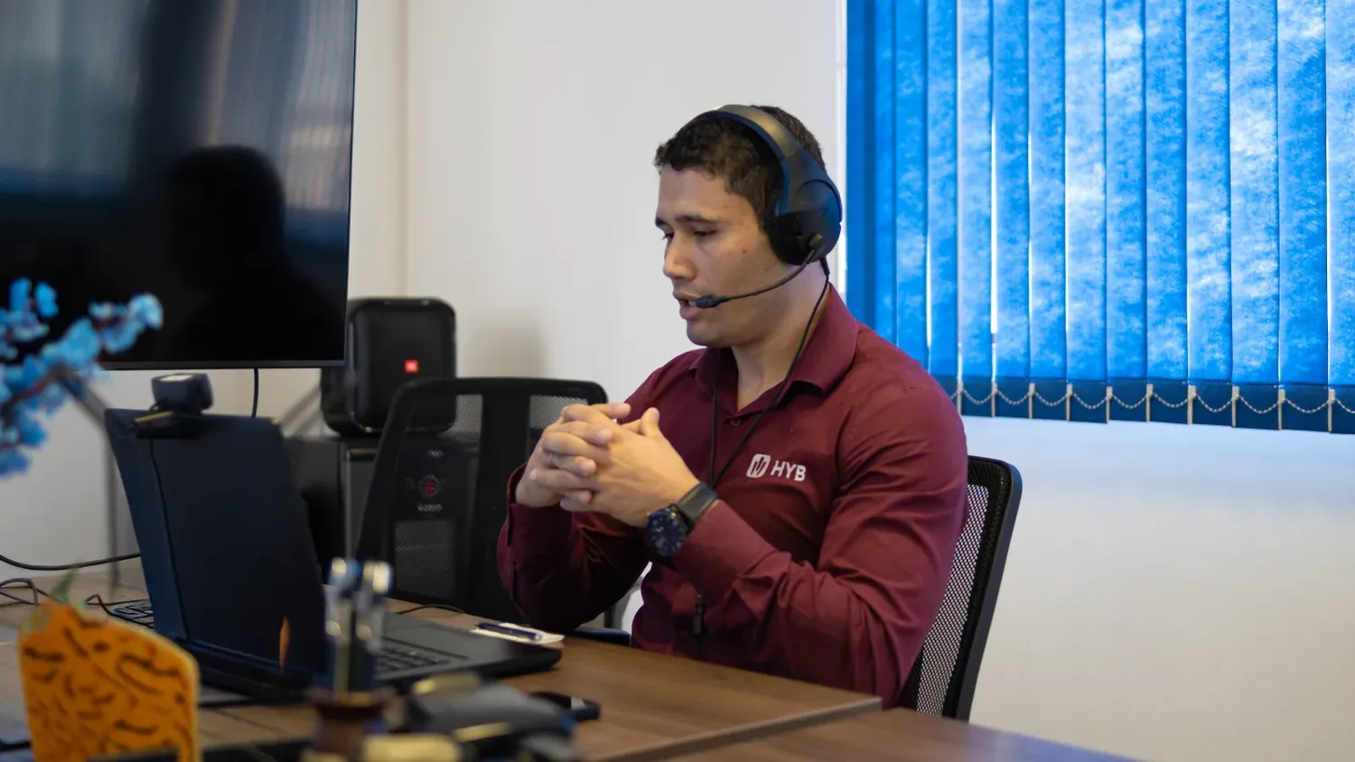 Consultor da Conplan, de camisa do HYB e headset, durante um atendimento por videochamada