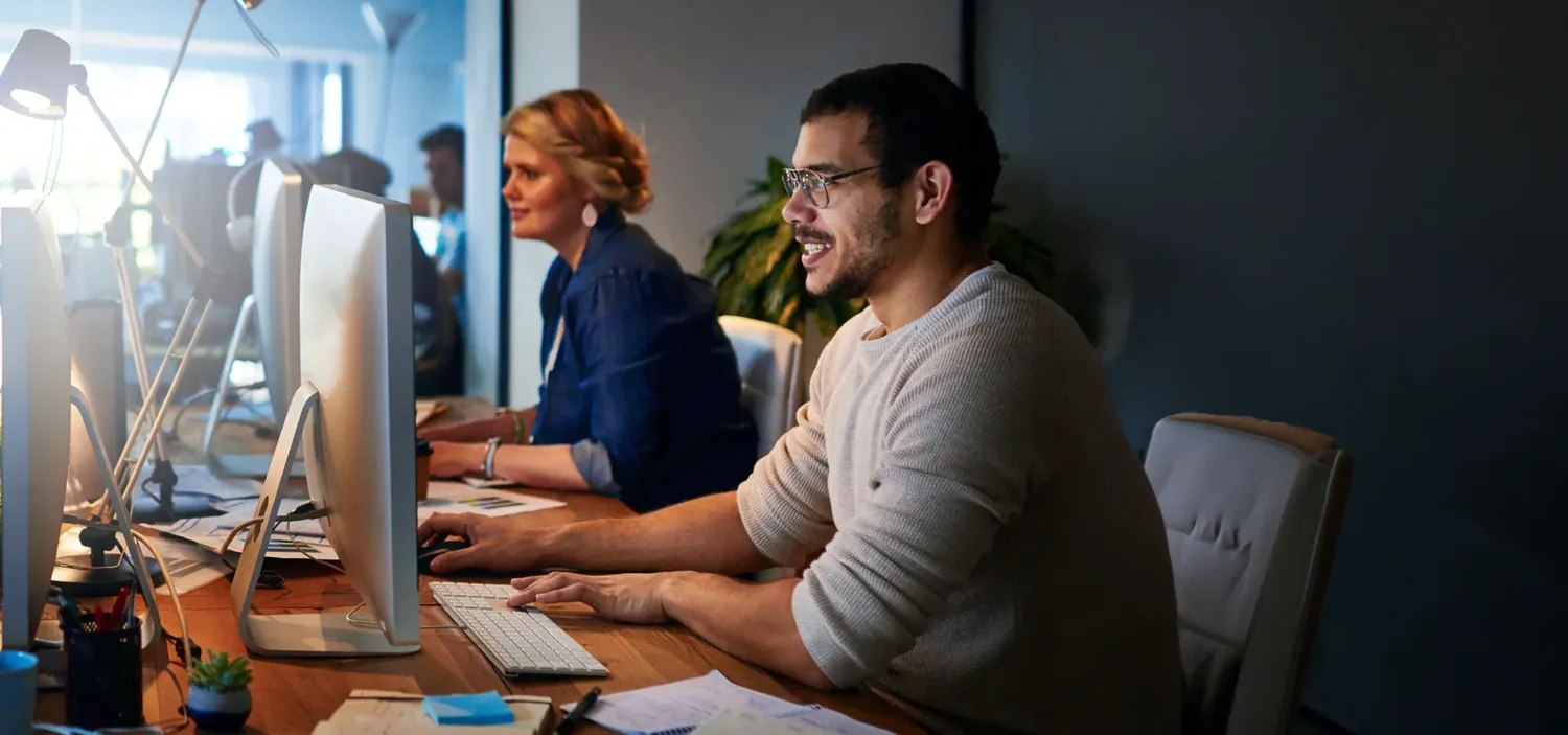 Equipe reunida em torno de uma mesa de trabalho, com computadores e anota��es