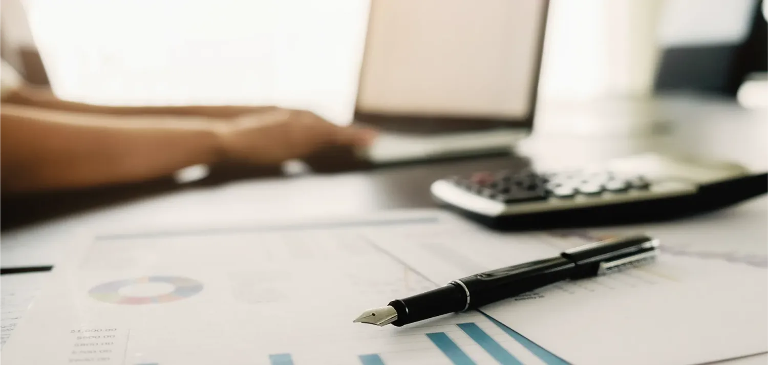 Caneta e calculadora sobre relat�rios impressos com gr�ficos
