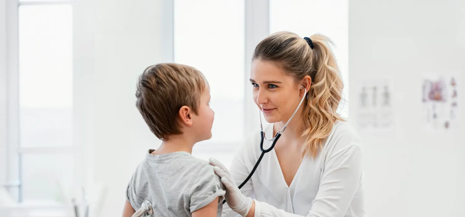 Pediatra auscultando uma crian�a pequena no colo, em sala de atendimento